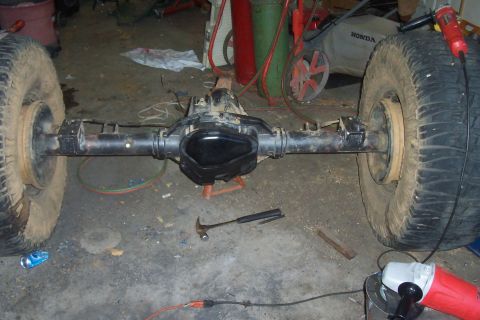 1994 Ford F-150 - Workshop scene shows a rear axle assembly with tires, tools, and equipment in the background.