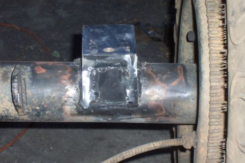 1994 Ford F-150 - A custom metal bracket is welded onto the rear axle of a vehicle, with a tire visible in the background.
