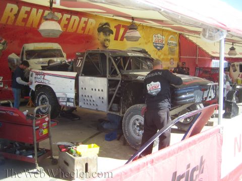1990 Ford Bronco - Crew members work on a number 17 off-road race truck under a red Ren Reeder pit canopy with Lucas Oil and Nissan banners.