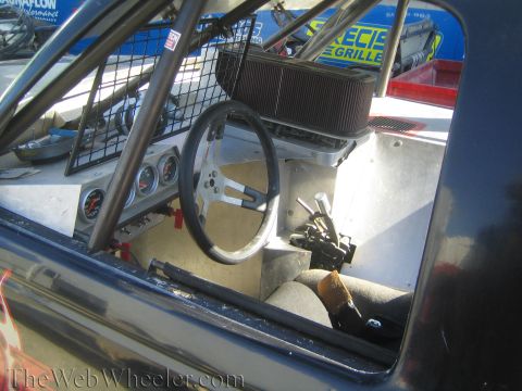 1990 Ford Bronco - bare cockpit of a tube-chassis off-road racer shows an aluminum steering wheel, gauge cluster and exposed air filter.