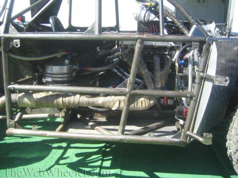 1990 Ford Bronco - close-up of an off-road racer's side shows the tube chassis, plumbing, air filter and heat-wrapped exhaust headers.
