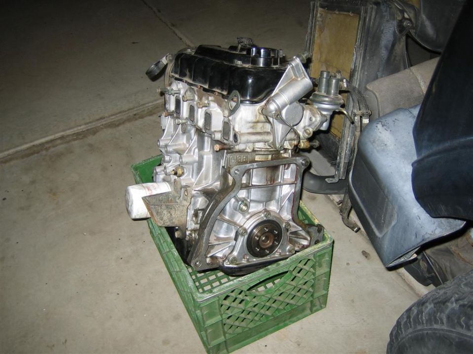 Engine block with oil filter and fuel pump, sitting in a green crate