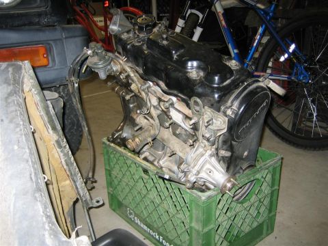1987 Suzuki Samurai - Engine removed from a vehicle and placed on a green crate, with a bicycle visible behind it.