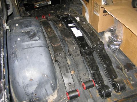 1987 Suzuki Samurai - Four leaf springs, likely for a vehicle suspension, are laid out inside a cargo area.