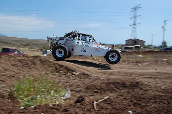White off-road buggy with number 1507 airborne over dirt track