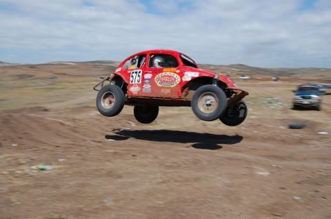 1992 Ford Explorer - A modified Volkswagen Beetle races across a dirt track, catching air during a jump.