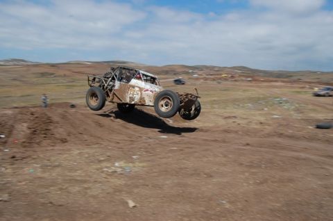 1992 Ford Explorer - A dirt buggy soars through the air over a dirt track, with other vehicles visible in the background.