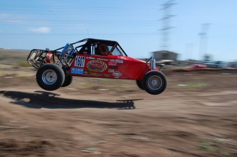 1992 Ford Explorer - Off-road buggy jumps over a dirt track, displaying sponsor decals.