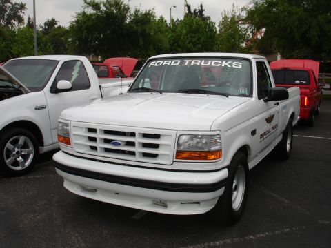 1993 Ford Taurus - A white Ford F-150 pickup truck is parked in a lot with other vehicles.