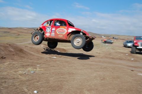 1992 Ford Explorer - Off-road racing Volkswagen Beetle catches air during a jump on a dirt track.
