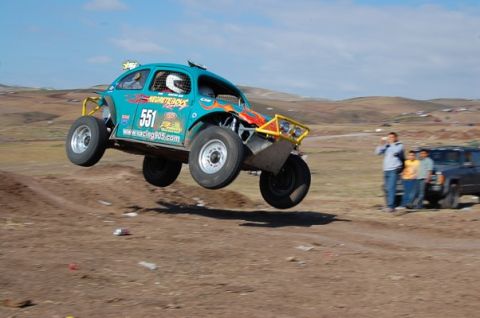 1992 Ford Explorer - A teal off-road dune buggy, marked with number 551, soars through the air during a race.