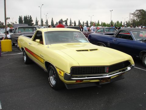 1993 Ford Taurus - A yellow 1970 Ford Ranchero is parked at an outdoor car show next to a blue vehicle.
