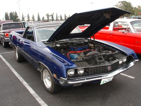 1993 Ford Taurus - A blue 1970 Ford Ranchero is parked with its hood open, revealing the engine. Another classic car is visible to the right.