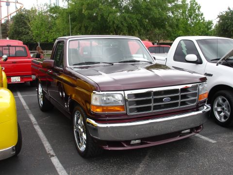 1993 Ford Taurus - Maroon Ford F-Series truck from the early 1990s is parked in a lot with other vehicles.