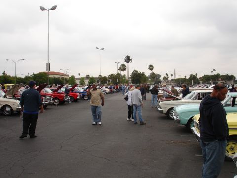 1993 Ford Taurus - A gathering of classic cars and attendees at an outdoor event under an overcast sky.
