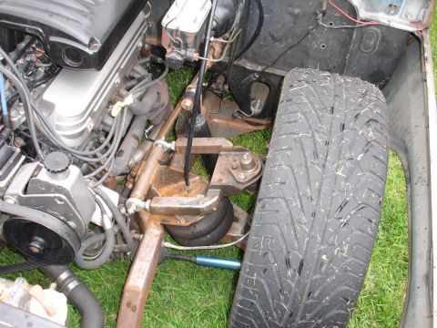 1993 Ford Taurus - The engine and front suspension system of a vehicle are visible, with a focus on the mechanical components and the tire.