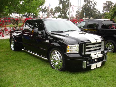 1993 Ford Taurus - A black Ford F-350 Super Duty pickup truck with chrome accents and racing stripes is parked on grass.