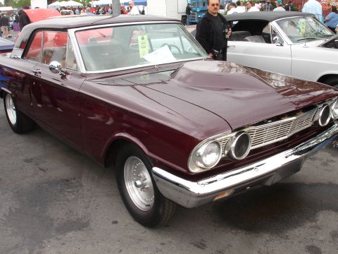 1993 Ford Taurus - A maroon 1963 Ford Falcon Sprint coupe is parked next to a white convertible at an outdoor car show.
