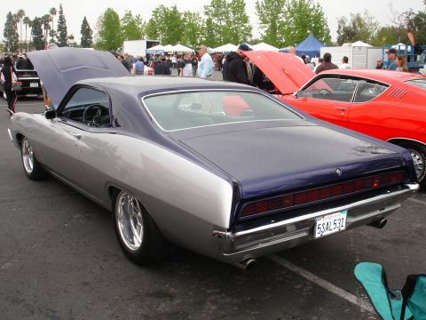 1993 Ford Taurus - A two-tone classic car is parked at an outdoor event with other vehicles and people around.