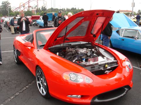 1993 Ford Taurus - A red convertible sports car with its hood open, revealing a custom engine and chrome wheels.