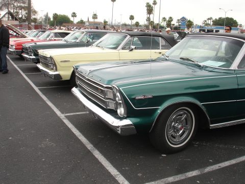 1993 Ford Taurus - A line of classic convertibles are parked in a lot, with a green 1965 model prominently in the foreground.