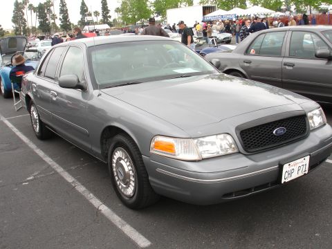 1993 Ford Taurus - A gray Ford Crown Victoria is parked in a lot, possibly at a car show or gathering.