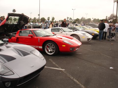 1993 Ford Taurus - A line of Ford GT sports cars are parked in a lot, with one red car prominently displayed with its hood open.