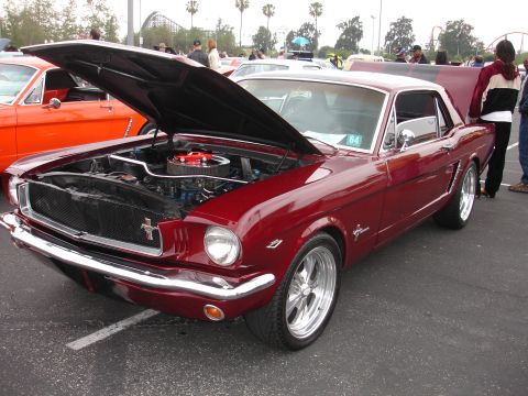 1993 Ford Taurus - A red 1965 Ford Mustang coupe is displayed with its hood open, revealing the engine bay.