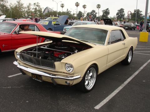 1993 Ford Taurus - A 1965 Ford Mustang coupe is displayed with its hood open at a car show, with other vehicles visible.