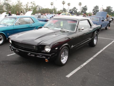 1993 Ford Taurus - A classic black Ford Mustang is parked at an outdoor event with other vehicles visible.