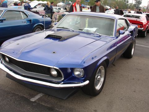 1993 Ford Taurus - A blue 1969 Ford Mustang is parked at an outdoor event with other vehicles visible.