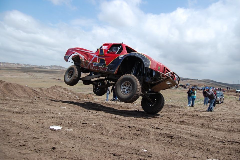 Red off-road truck airborne over dirt track