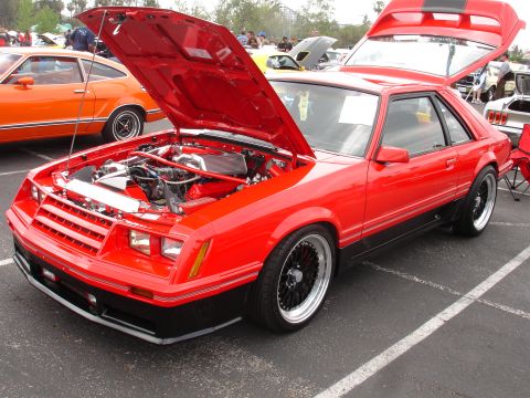 1993 Ford Taurus - Red coupe with hood and trunk open, parked next to an orange car at an outdoor event.
