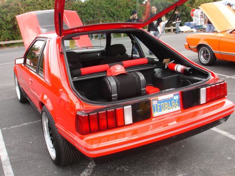 1993 Ford Taurus - A red hatchback car is parked with its hood and trunk open, revealing its interior and engine bay.