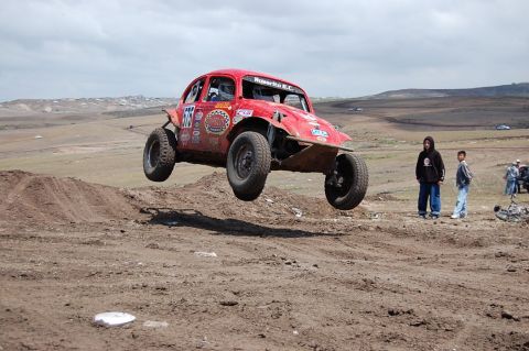 1992 Ford Explorer - A red off-road buggy soars through the air during a race, with spectators watching from the side.