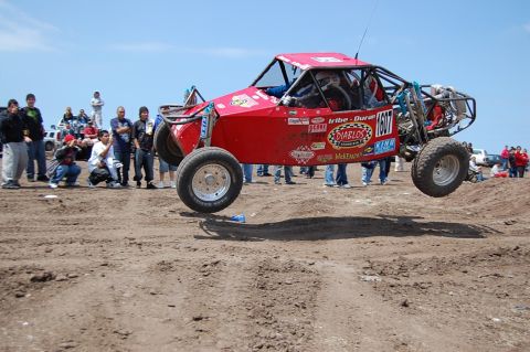 1992 Ford Explorer - Off-road buggy takes flight during a race event with spectators observing.
