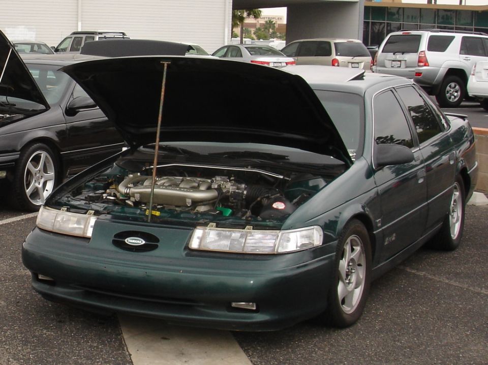 Green 1993 Ford Taurus with hood open, showing engine and strut tower brace