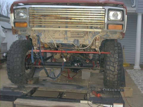 1986 Ford Bronco - The front of a lifted Ford Bronco is shown with its grille and headlights, revealing suspension modifications.