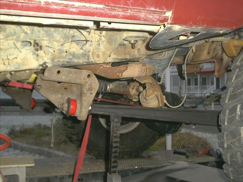 1986 Ford Bronco - Close-up view of the undercarriage and suspension system of a red vehicle.