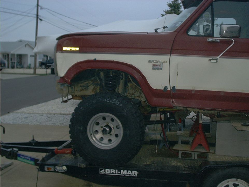 1986 Ford Bronco on a trailer, front quarter view, showing lifted suspension and two-tone paint