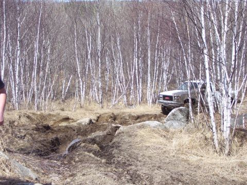 1996 Ford Bronco - A GMC pickup truck drives through a challenging off-road course in a wooded area.