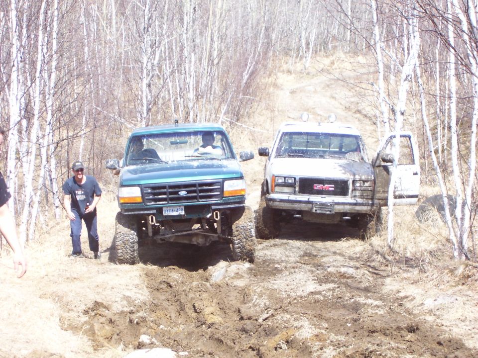 1996 Ford Bronco front view, green, off-roading with a GMC truck