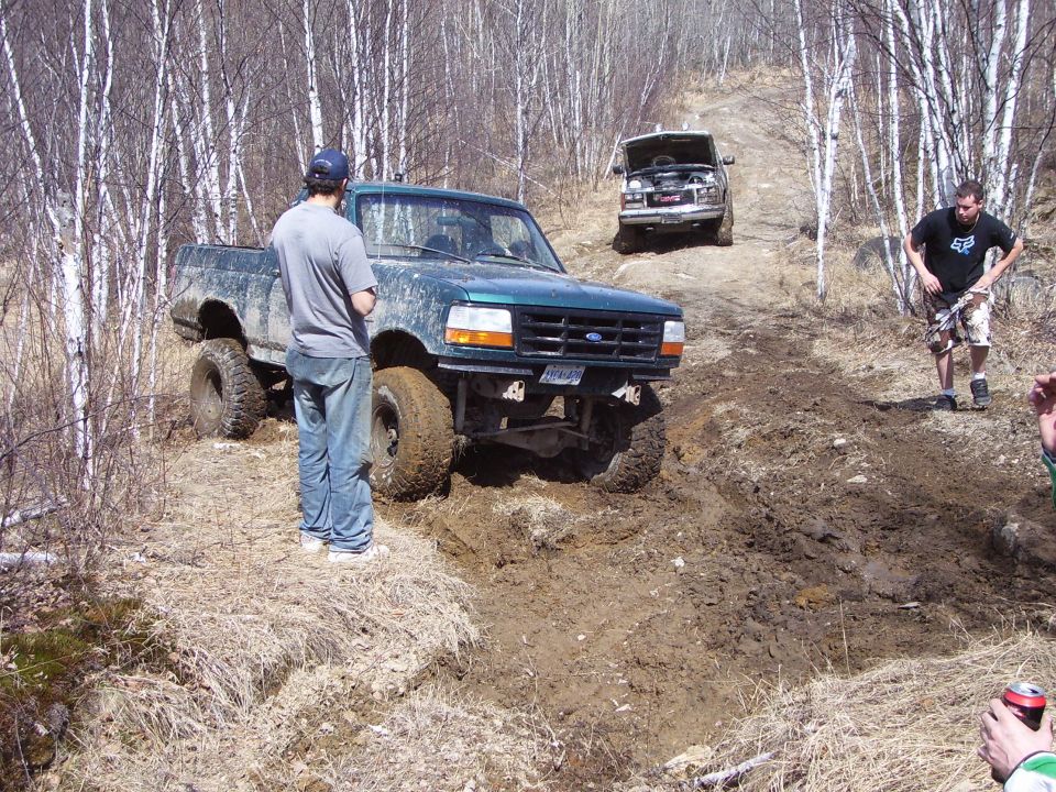 Green pickup truck with lifted suspension stuck in mud, front view