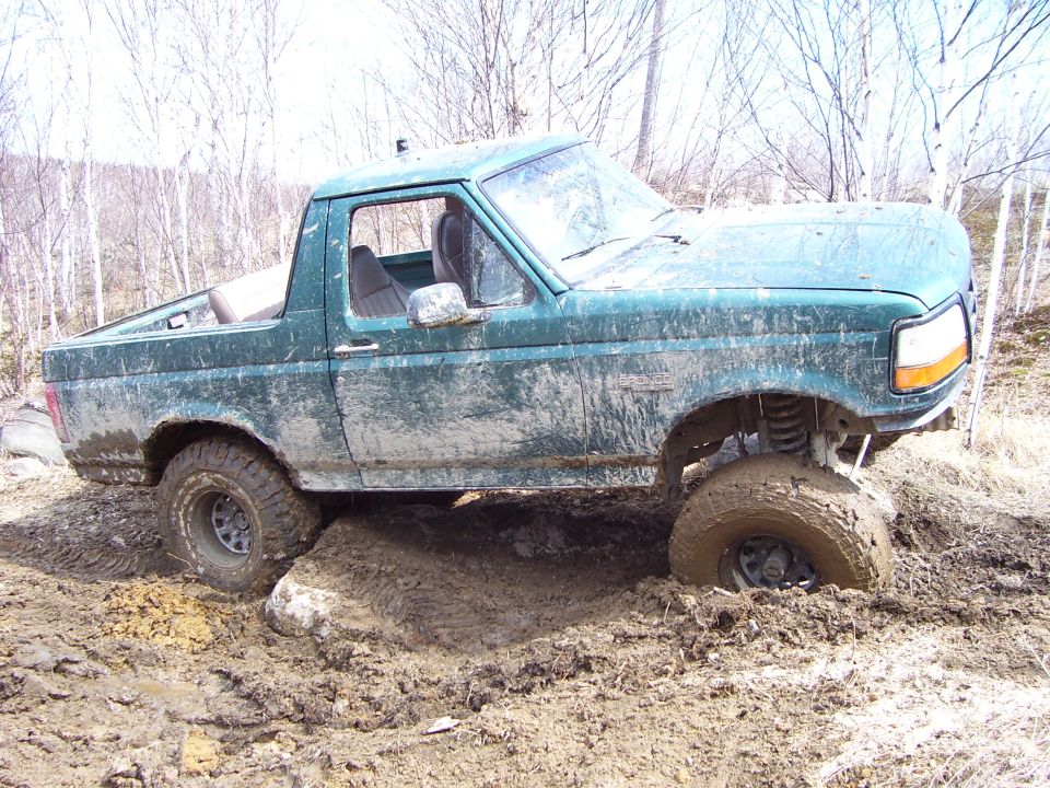 Green 1996 Ford Bronco stuck in mud, 3/4 front view