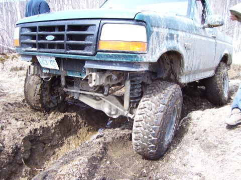 1996 Ford Bronco - This Ford F-Series truck is stuck in a muddy ditch, showing its front suspension and large off-road tires.