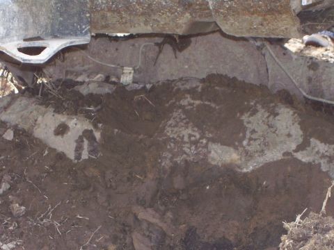 1996 Ford Bronco - The underside of a vehicle is obscured by dirt and mud, making identification difficult.