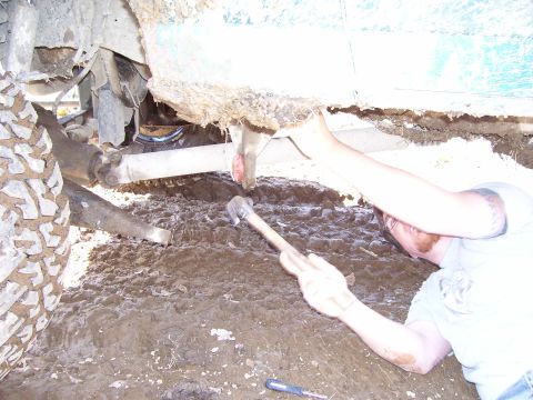 1996 Ford Bronco - Working on the undercarriage of a vehicle in the mud.