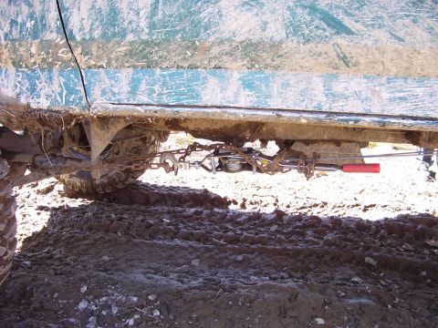 1996 Ford Bronco - Undercarriage view of a teal vehicle, showing a winch and chains, stuck in mud.