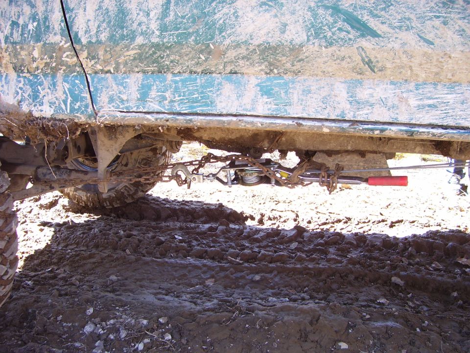 Undercarriage of a teal vehicle with winch and chains attached to frame