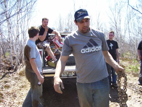 1996 Ford Bronco - Men gathered around the rear of a pickup truck in a wooded area.